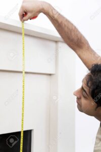 26257088 el hombre de medicion repisa de la chimenea con una cinta metrica