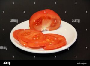 rodajas de tomate en rodajas sobre plato blanco aisladas sobre fondo negro rodajas de tomates maduros en un plato tomates aislados sobre fondo negro 2gxw786